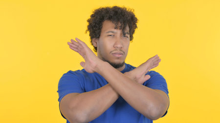 Casual African Man Rejecting with Arm Gesture on Yellow Background