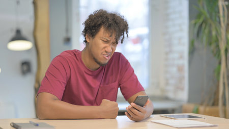 Upset Young African Man Reacting to Loss on Smartphone