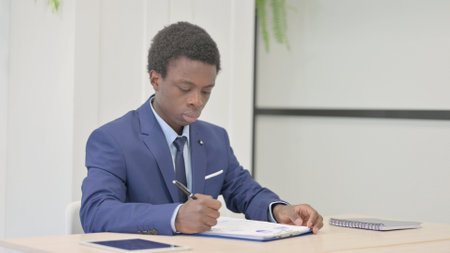 African Businessman Doing Paperwork in Office