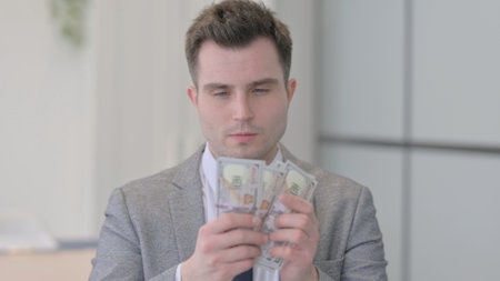 Portrait of Young Businessman Counting Dollar