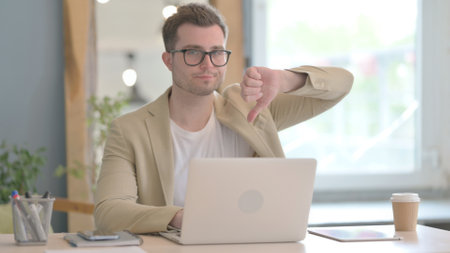 Thumbs Down by Young Businessman Working on Laptopの写真素材