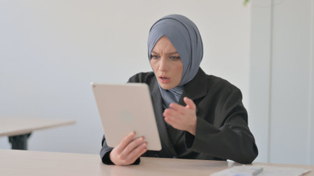 Muslim Businesswoman Upset by Loss on Tabletの写真素材