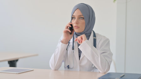 Muslim Female Doctor Talking on Phone in Clinicの写真素材