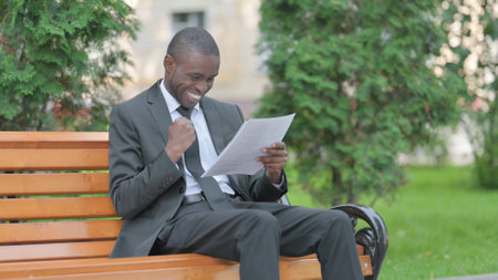 African Businessman Celebrating while Reading Documents Outdoorの写真素材
