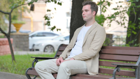 Casual Young Man Standing up and Leaving Bench Outdoorの写真素材