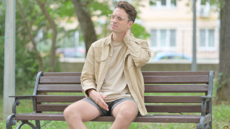 Tired Casual Young Man Sitting Outdoor with Neck Painの写真素材