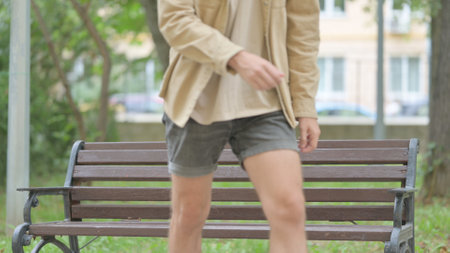 Casual Young Man Standing up and Leaving Bench Outdoorの写真素材