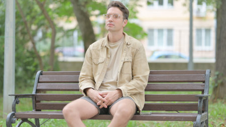 Serious Casual Young Man Sitting Outdoorの写真素材