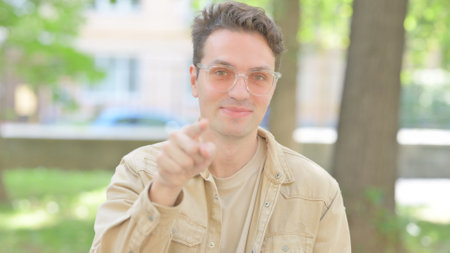 Outdoor Portrait of Casual Young Man Pointing at Cameraの写真素材