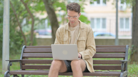Casual Young Man Working on Laptop Outdoorの写真素材