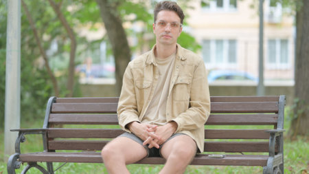 Casual Young Man Looking at Camera while Sitting Outdoorの写真素材