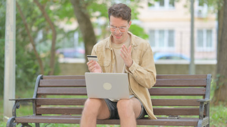 Casual Young Man Upset by Online Payment Failure on Laptop Outdoorの写真素材