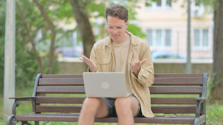 Casual Young Man Shocked by Loss on Laptop Outdoorの写真素材