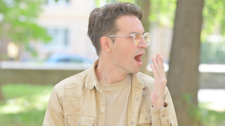 Tired Young Man Yawning Outdoorの写真素材