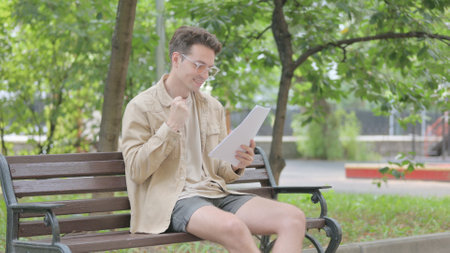 Modern Young Man Reading and Celebrating Documents Outdoorの写真素材