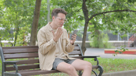 Young Man Doing Video Chat on Phone Outdoorの写真素材