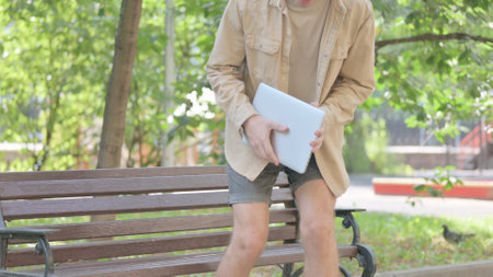 Man use of digital tablet while sitting on the bench in the parkの写真素材