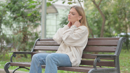 Casual Young Woman Sitting Outdoor with Neck Painの写真素材