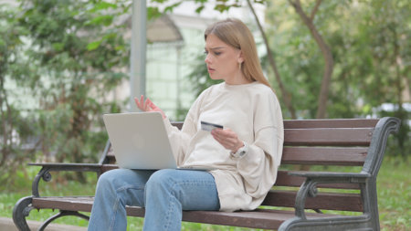 Casual Young Woman Upset by Online Payment Failure on Laptop Outdoorの写真素材