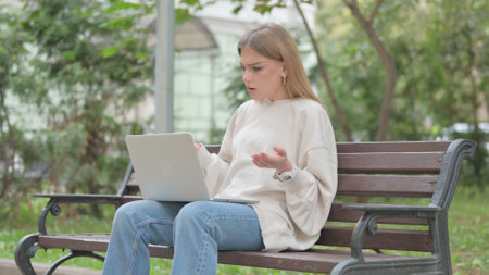 Casual Young Woman Shocked by Loss on Laptop Outdoorの写真素材