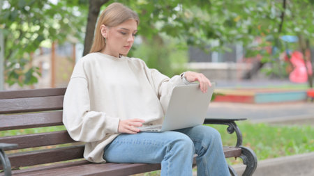 Young Woman Leaving Bench Outdoor after Working on Laptopの写真素材