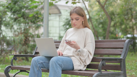 Casual Young Woman Working on Laptop and Smartphoneの写真素材