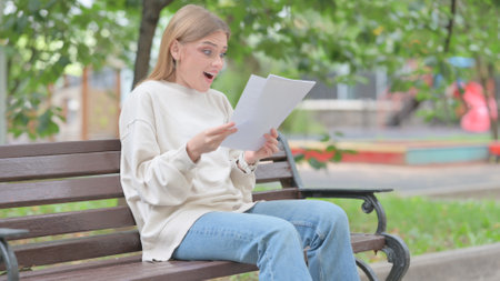 Young Woman Celebrating and Reading Documents Outdoorの写真素材