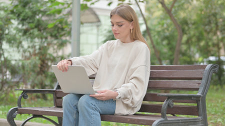 Casual Young Woman Coming, Sitting on Bench and Working on Laptopの写真素材