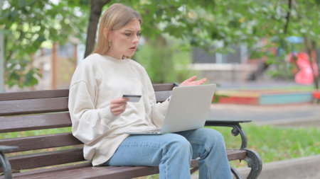 Young Woman Upset by Online Payment Failure on Laptop Outdoorの写真素材
