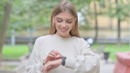 Woman Browsing Internet on Smart Watch Outdoorの写真素材