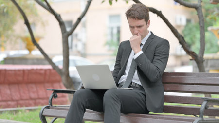 Coughing Businessman Using Laptop Outdoorの写真素材