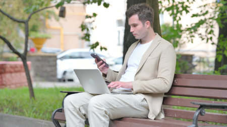 Casual Young Man Working on Laptop and Smartphoneの写真素材