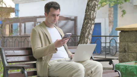 Young Man Working on Laptop and Smartphoneの写真素材