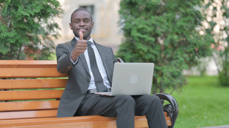 Thumbs Up by African Businessman on Laptop Outdoorの写真素材