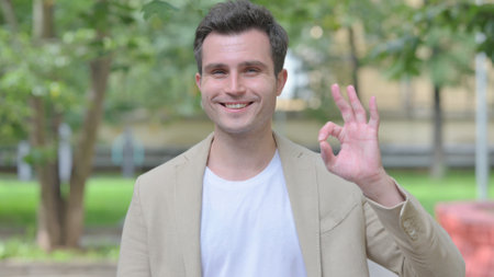 Outdoor Portrait of Young Man Doing Ok Signの写真素材