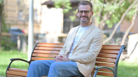 Middle Aged Man Smiling at Camera while Sitting Outdoorの写真素材