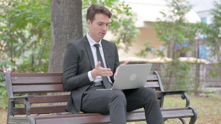 Online Video Chat by Young Businessman on Laptop Outdoorの写真素材