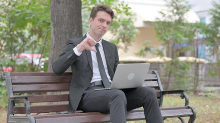 Thumbs Down by Young Businessman on Laptop Outdoorの写真素材
