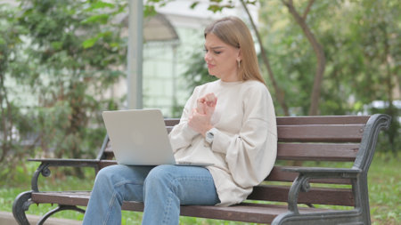 Casual Young Woman Using Laptop with Risk Pain Outdoorの写真素材