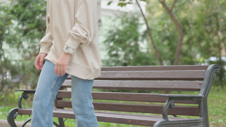 Casual Young Woman Standing up and Leaving Bench Outdoorの写真素材