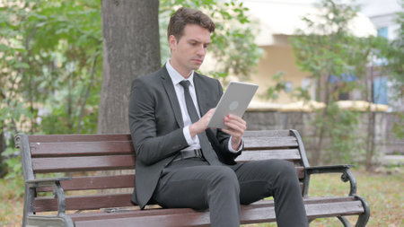 Young Businessman using Tablet while Sitting Outdoor on a Benchの写真素材