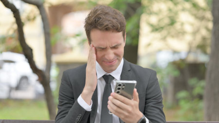 Upset Young Businessman get Shocked on Smartphone Outdoorの写真素材