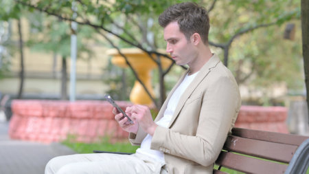 Side View of Young Man using Smartphone Outdoorの写真素材