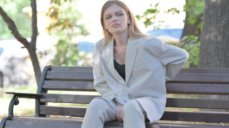 Young Businesswoman Sitting on Bench with Back Painの写真素材