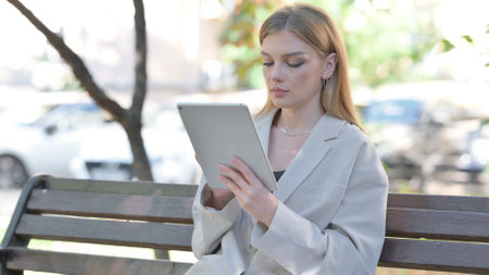 Young Businesswoman using Tablet while Sitting on Benchの写真素材