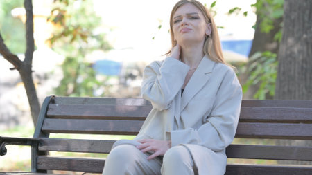 Young Businesswoman Sitting on Bench with Neck Painの写真素材