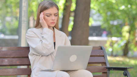 Young Businesswoman with Headache Working on Laptop Outdoorの写真素材