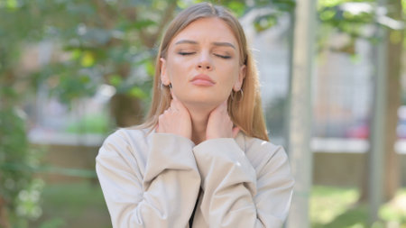 Tired Businesswoman with Neck Muscle Pain Outdoorの写真素材