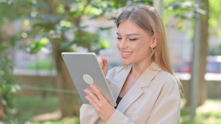 Businesswoman Celebrating Success on Tablet Outdoorの写真素材