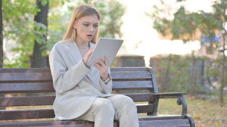 Young Business Lady on Tablet while Sitting on Benchの写真素材